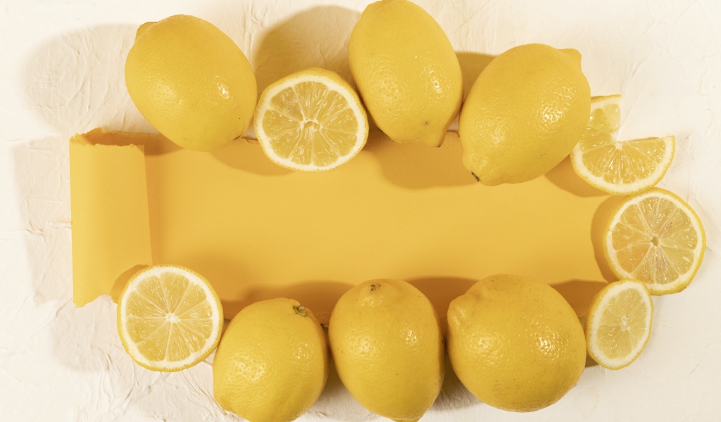 Желтые лимоны на белом фоне с листом бумаги