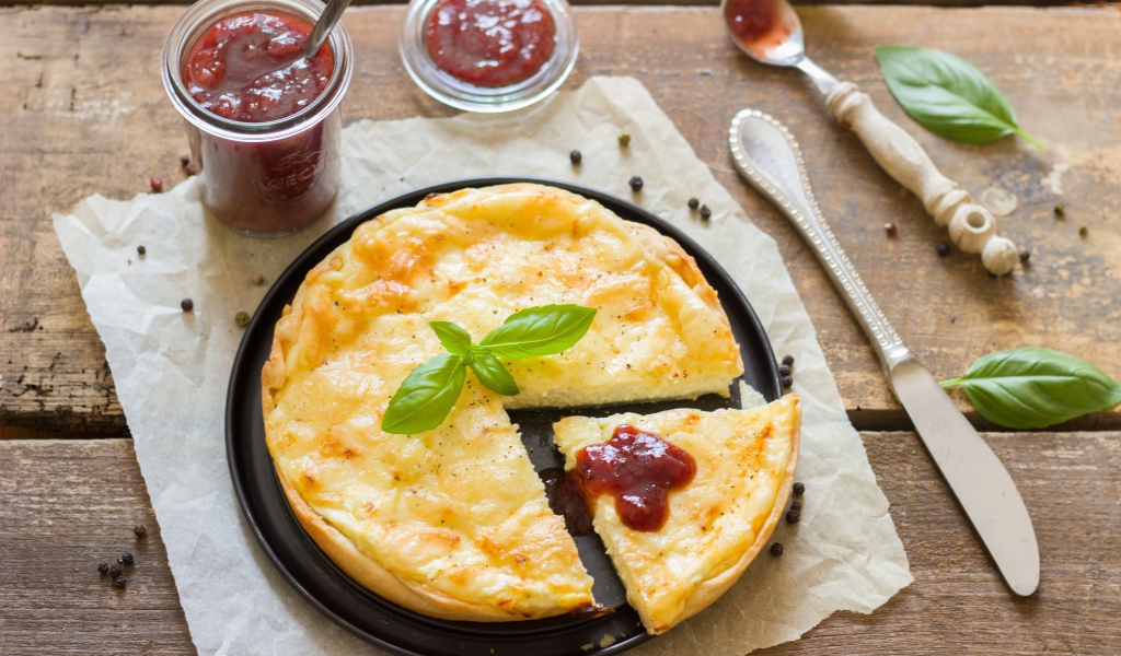 Пирог с сыром на столе с кетчупом и базиликом
