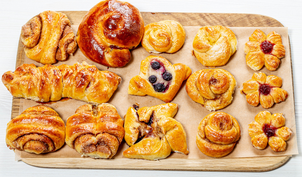 Разная свежая выпечка на доске на белом фоне