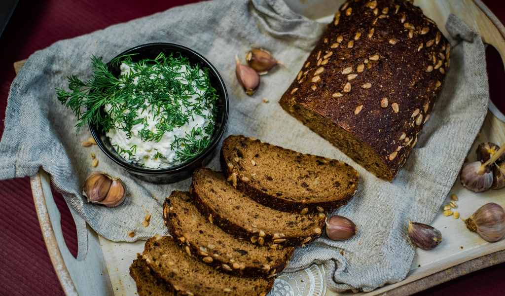 Свежий хлеб с зернами на столе с соусом и чесноком