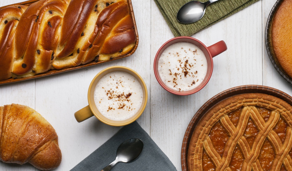 Свежая выпечка и две кружки молока на столе