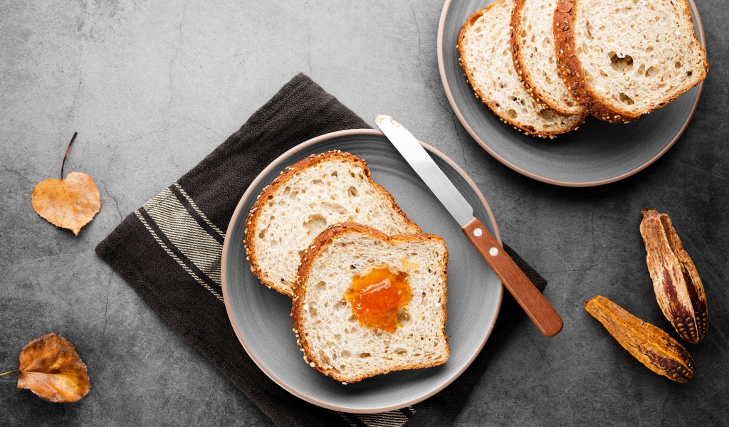 Куски хлеба с джемом на сером столе 
