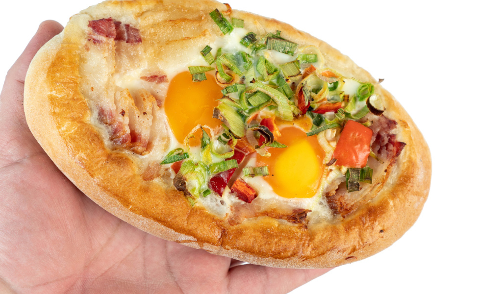 Вкусный свежий хачапури с яйцом и беконом в руке