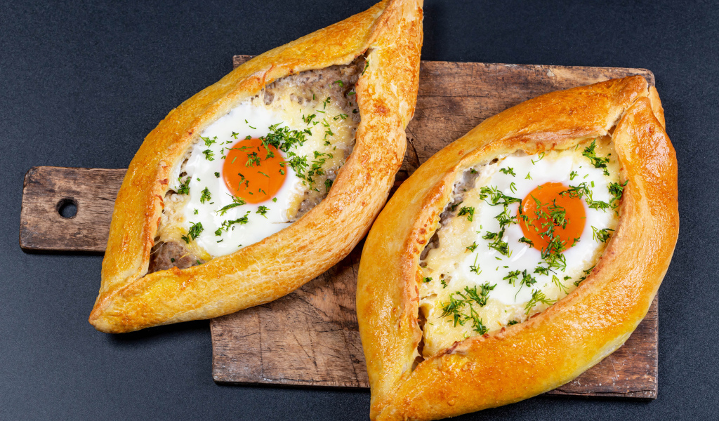 Два больших свежих хачапури с яйцом на доске