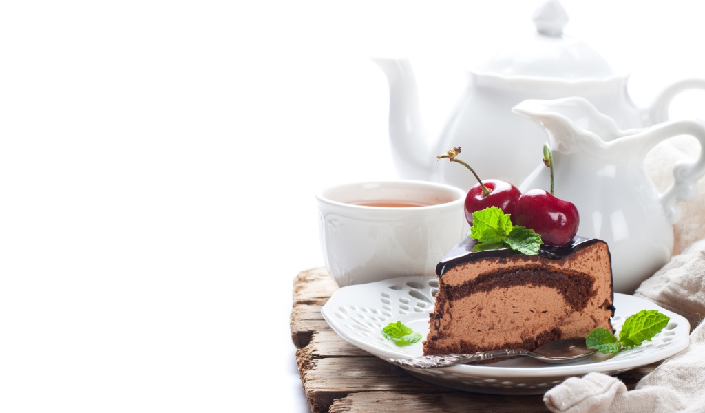 Кусок торта с ягодами черешни на столе с чаем