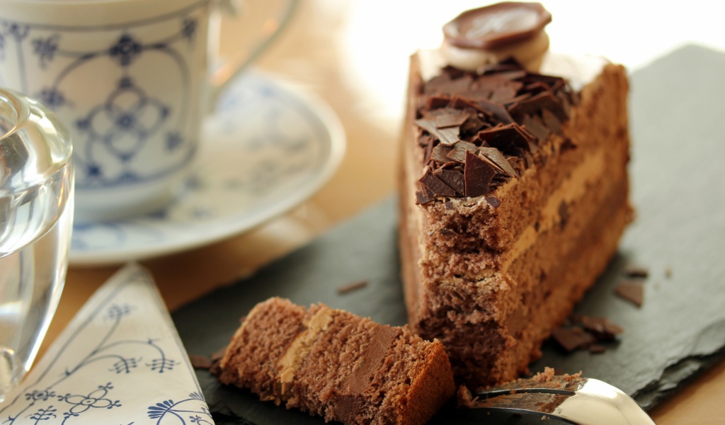 Кусок торта с шоколадом на столе с кофе