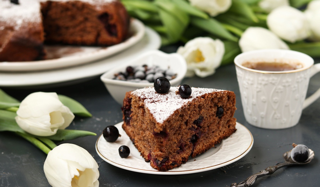 Кусок пирога со смородиной на столе с тюльпанами 