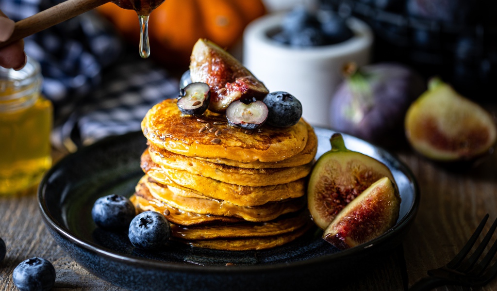 Аппетитные оладьи на тарелке с ягодами черники и инжиром