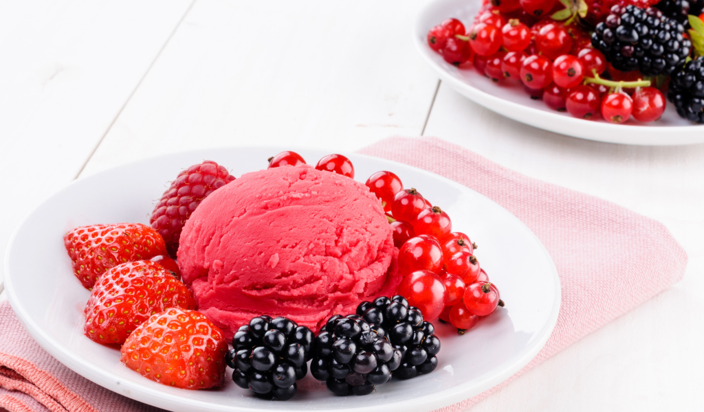 Шарик фруктового мороженого с ягодами на белой тарелке