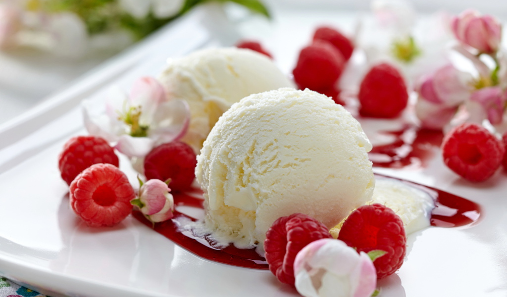 Шарики сливочного мороженого на тарелке с малиной и цветами
