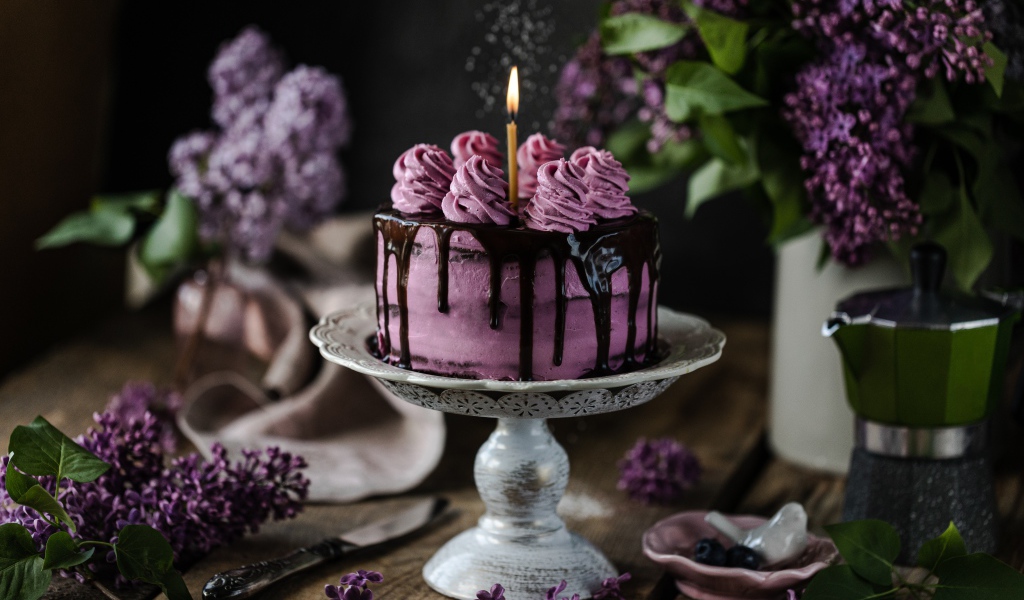 Ягодный торт со свечой на столе с сиренью 