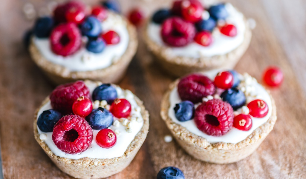 Пирожные с кремом и ягодами на столе крупным планом