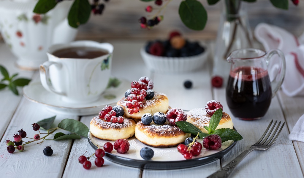 Сырники на столе с ягодами и чаем на завтрак