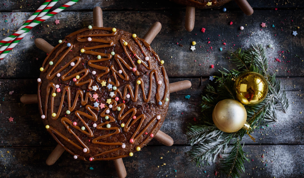 Шоколадное пирожное на столе с еловыми игрушками 