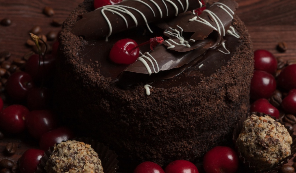 Шоколадный торт с конфетами и вишней на столе 