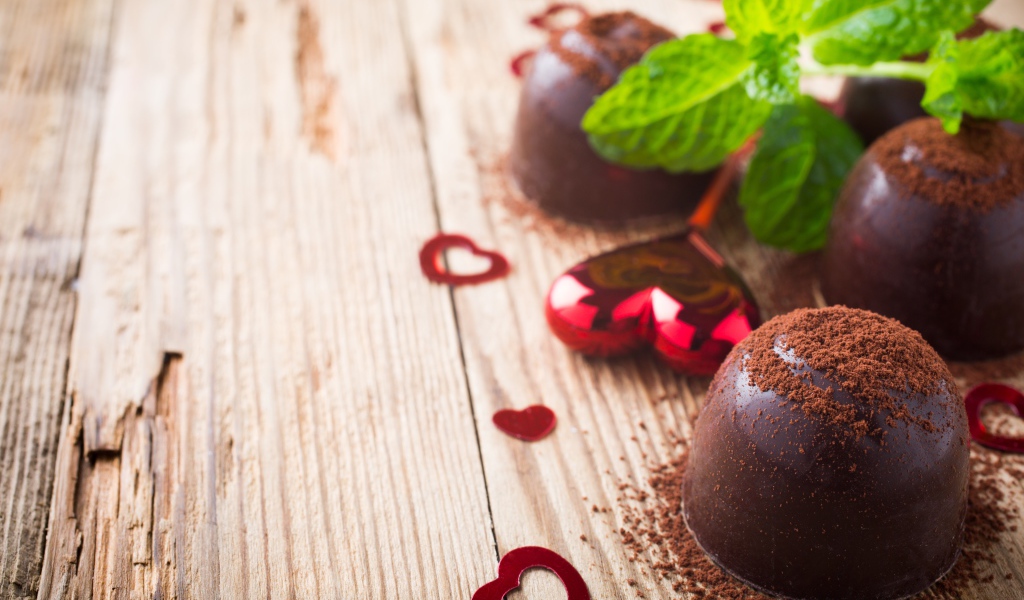 Шоколадные конфеты с какао на столе с мятой и сердечками