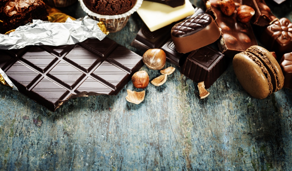 Шоколад на столе с орехами, кексами и конфетами 