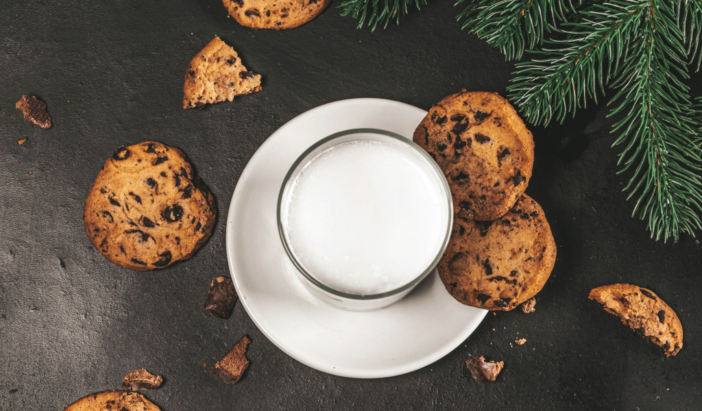 Печенье с шоколадом на столе со стаканом молока 