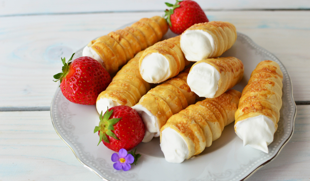 Пирожные с кремом на тарелке с клубникой