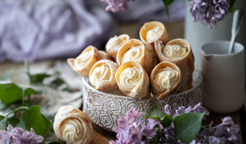 Трубочки с кремом на столе с цветами сирени