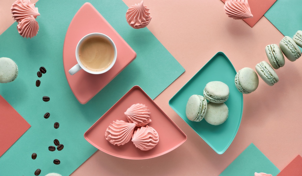 Чашка какао на столе с зефиром и десертом макарон 