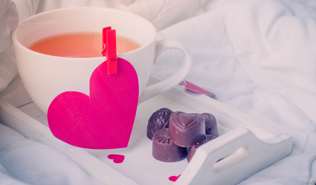 Чашка кофе с красным сердцем и шоколадными конфетами 