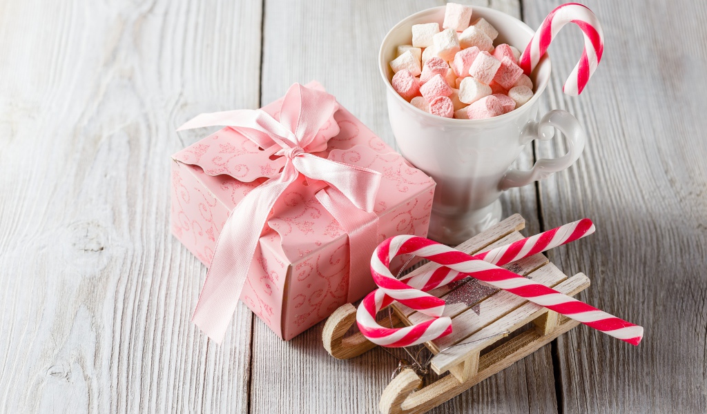 Чашка с маршмеллоу на столе с игрушечными санками и подарком