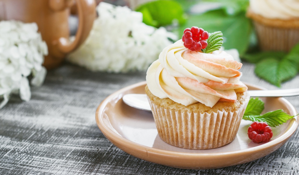 Кекс с кремом и малиной на столе