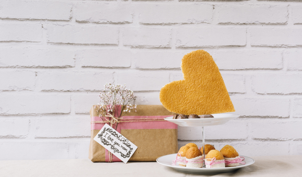 Кексы на тарелке на столе с подарком для любимой 