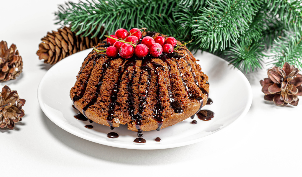 Вкусный кекс с шоколадом и красной смородиной на столе с еловой веткой и шишками