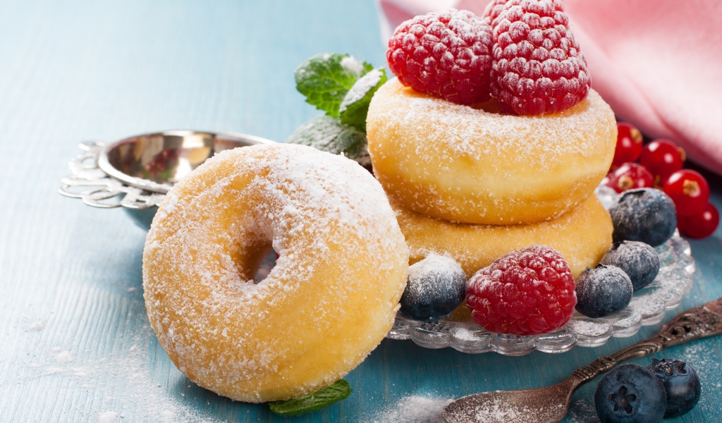 Вкусные пышные пончики с ягодами черники и малины с сахарной пудрой 