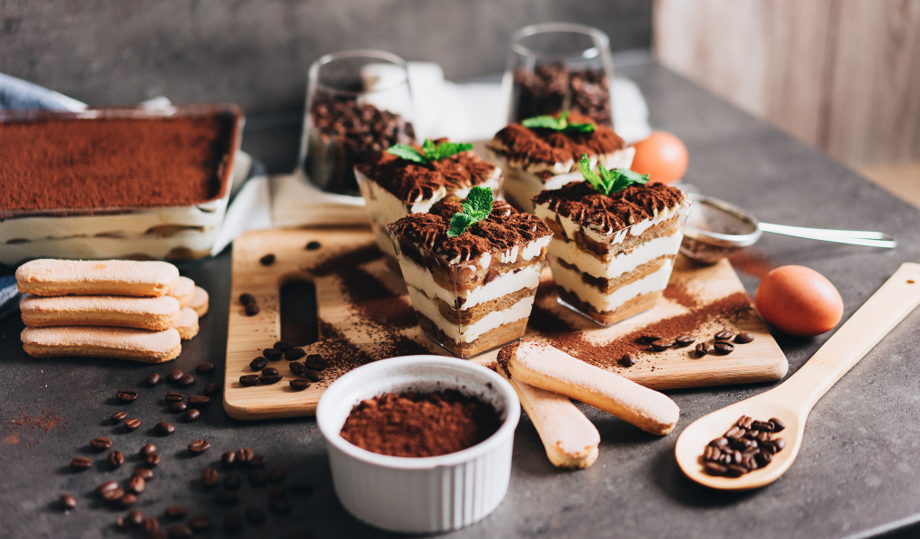 Аппетитный десерт тирамису в креманках на столе с кофейными зернами