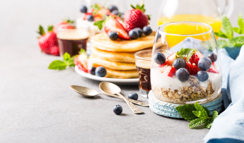 Оладьи на столе с ягодами, мюсли и кофе