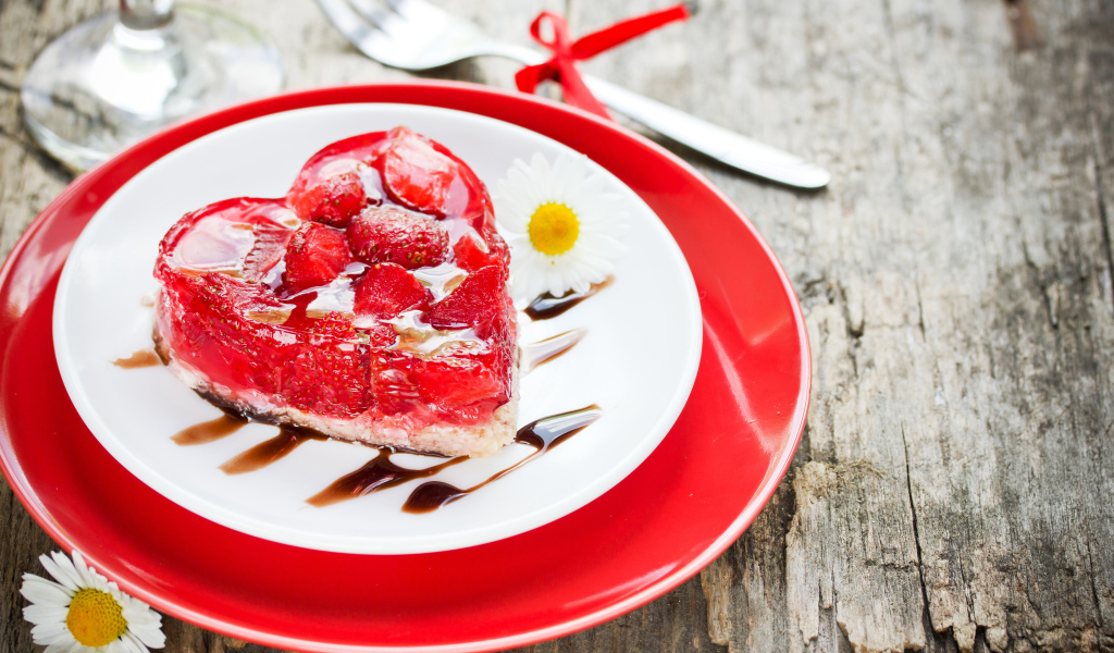 Пирожное с клубникой в форме сердца на тарелке с ромашками