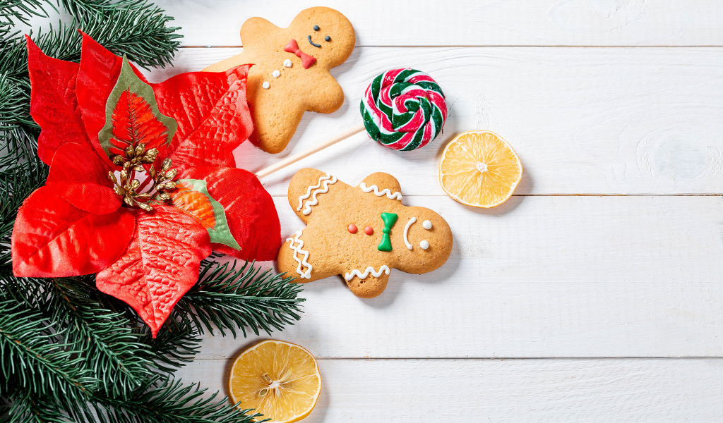 Праздничное печенье с леденцом и еловой веткой на столе 