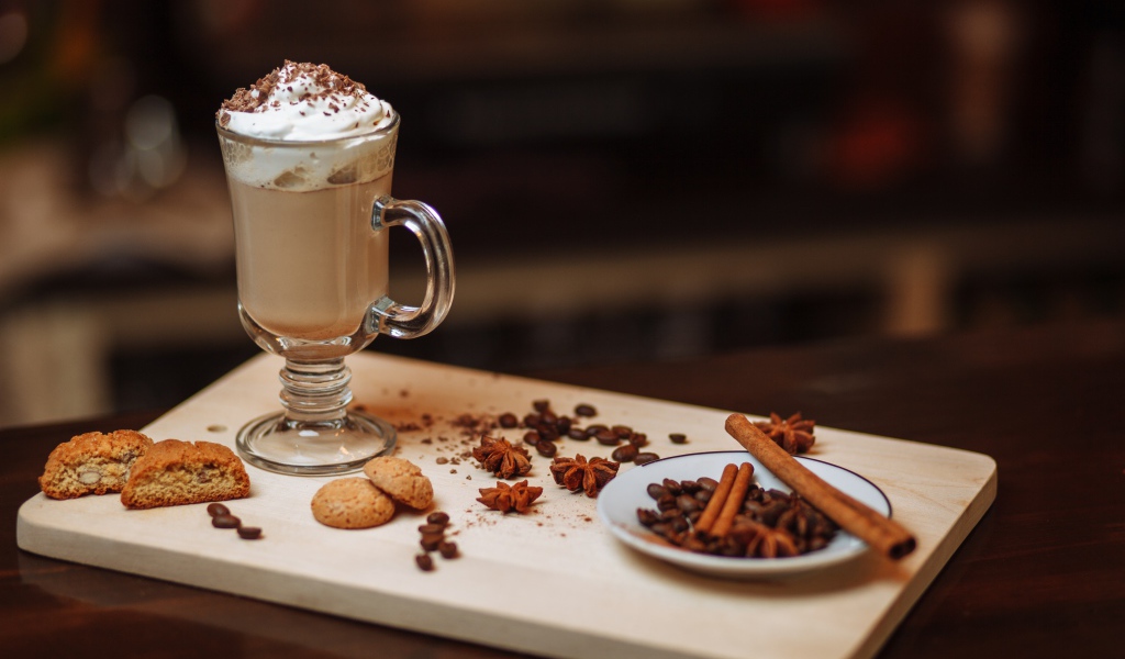 Горячее какао со сливками на столе с печеньем, зернами кофе и пряностями 