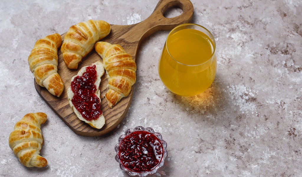 Сок на столе с круассанами и джемом