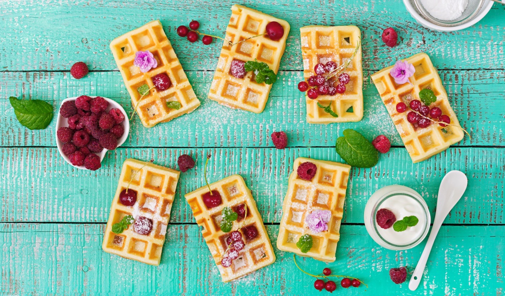 Большие сладкие вафли с ягодами и сахарной пудрой на столе 