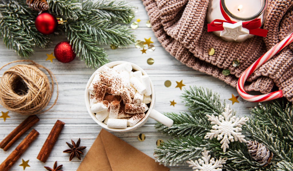 Кружка с маршмеллоу на столе с еловыми ветками и свечой