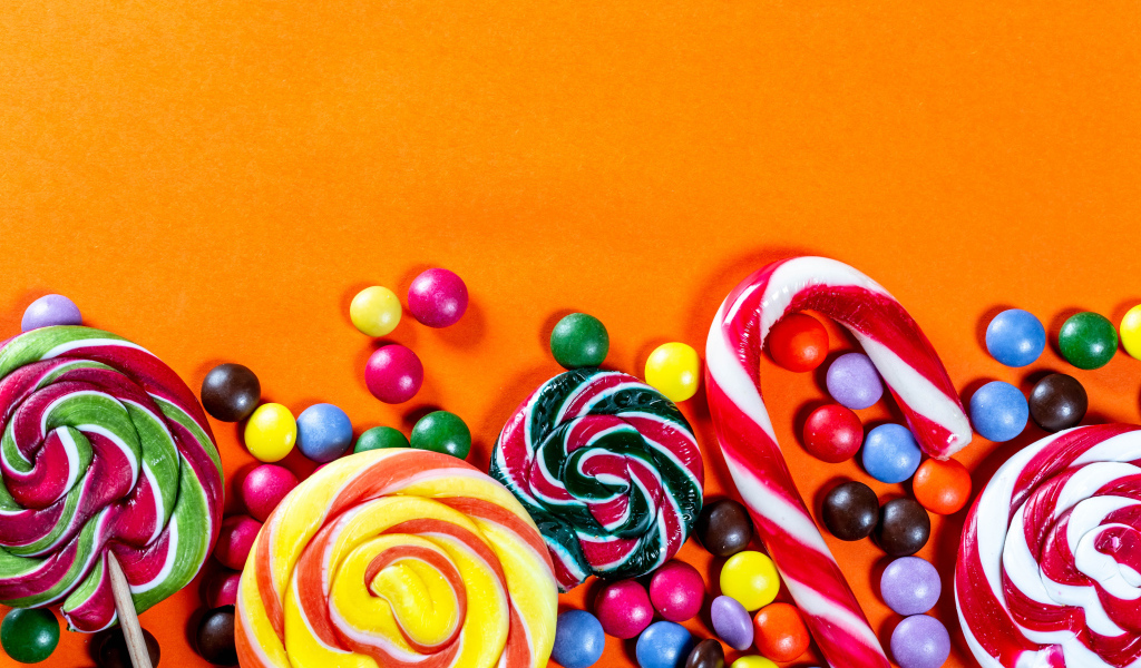 Разноцветные конфеты на оранжевом фоне