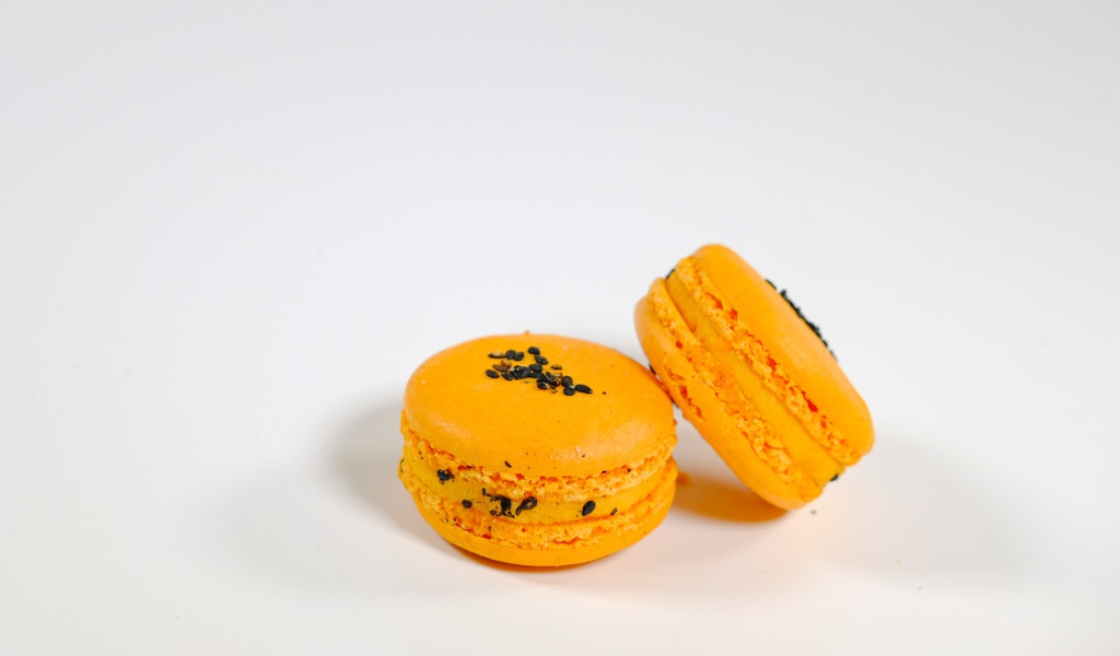 Оранжевый десерт макарон на сером фоне