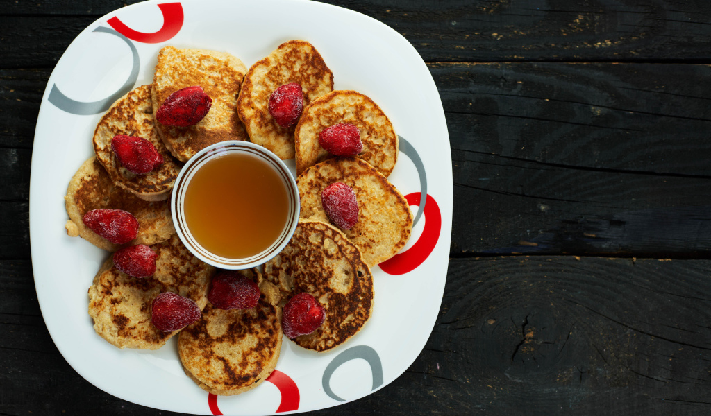 Оладьи на тарелке с клубникой и медом