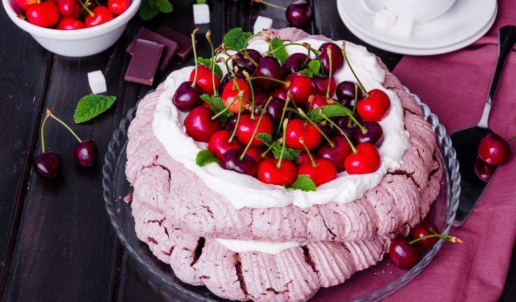 Торт Павлова со сливками и ягодами черешни на столе