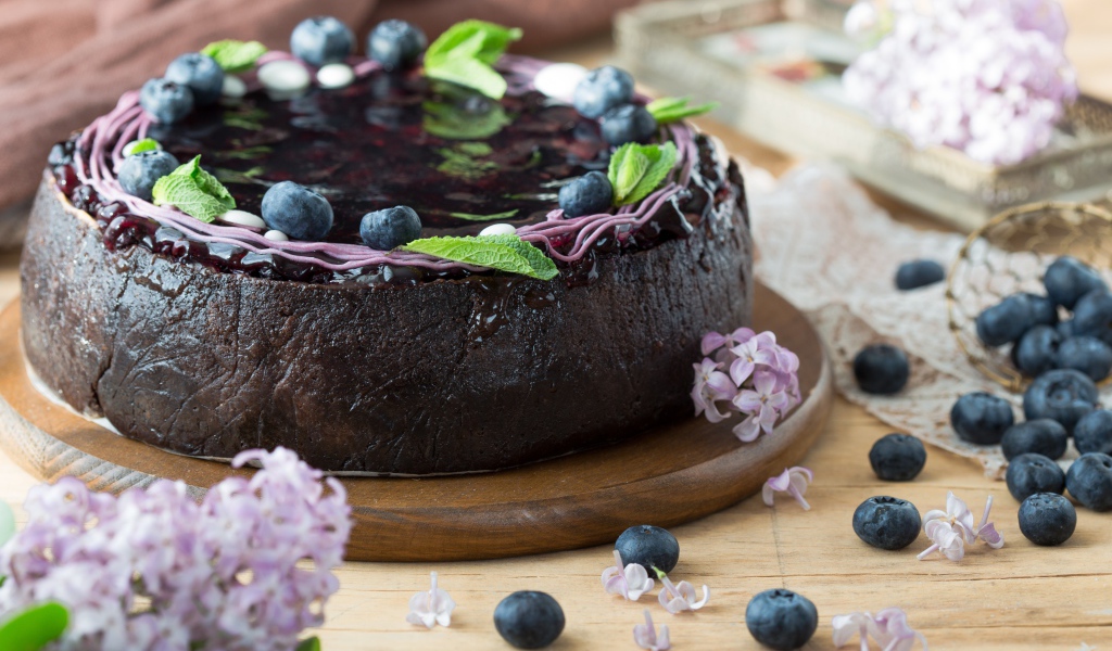 Пирог с джемом и ягодами черники на столе с сиренью 