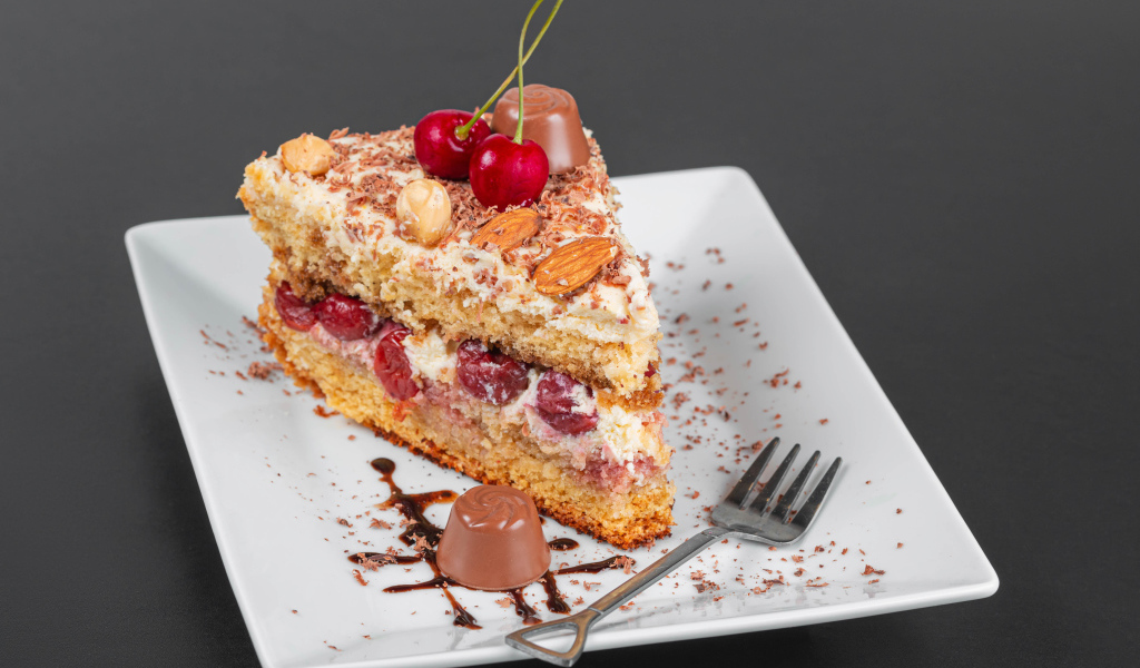 Кусок торта с ягодами вишни и миндальным орехом