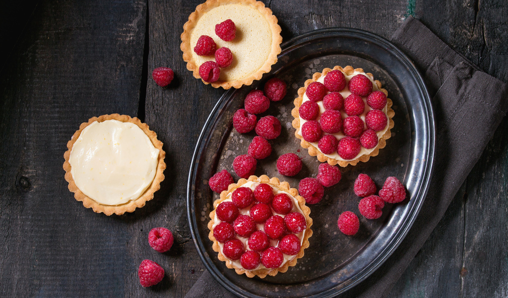 Кексы с кремом на блюде с малиной 