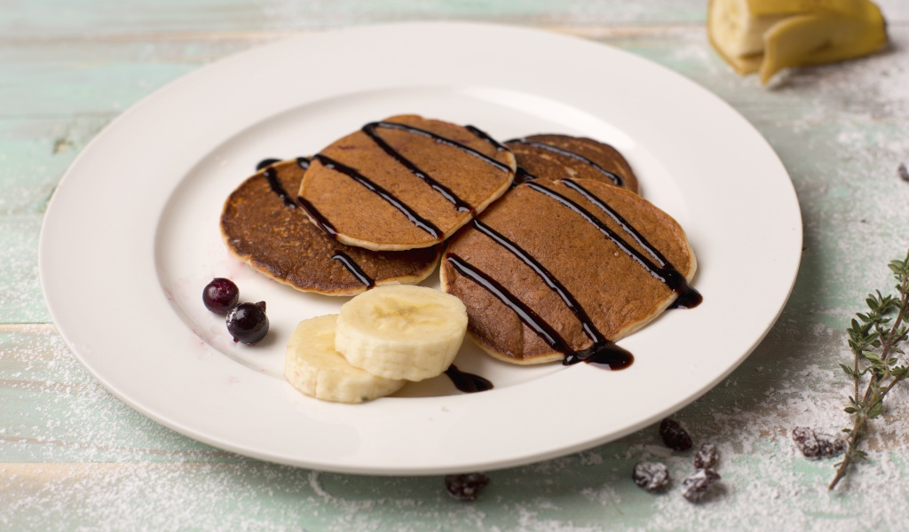 Румяные оладьи с бананом на белой тарелке 