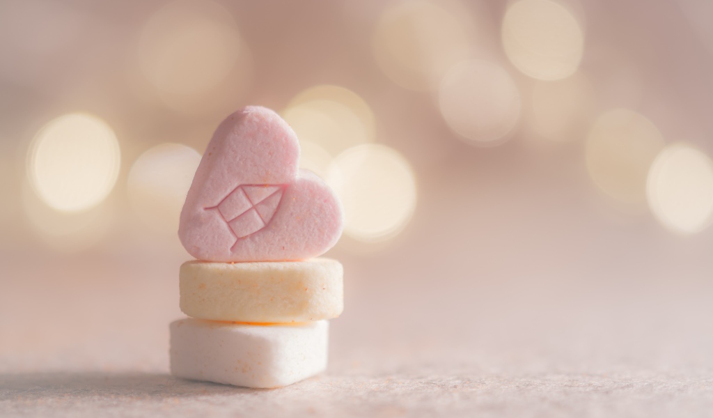 Маленькие конфеты в форме сердца на розовом фоне