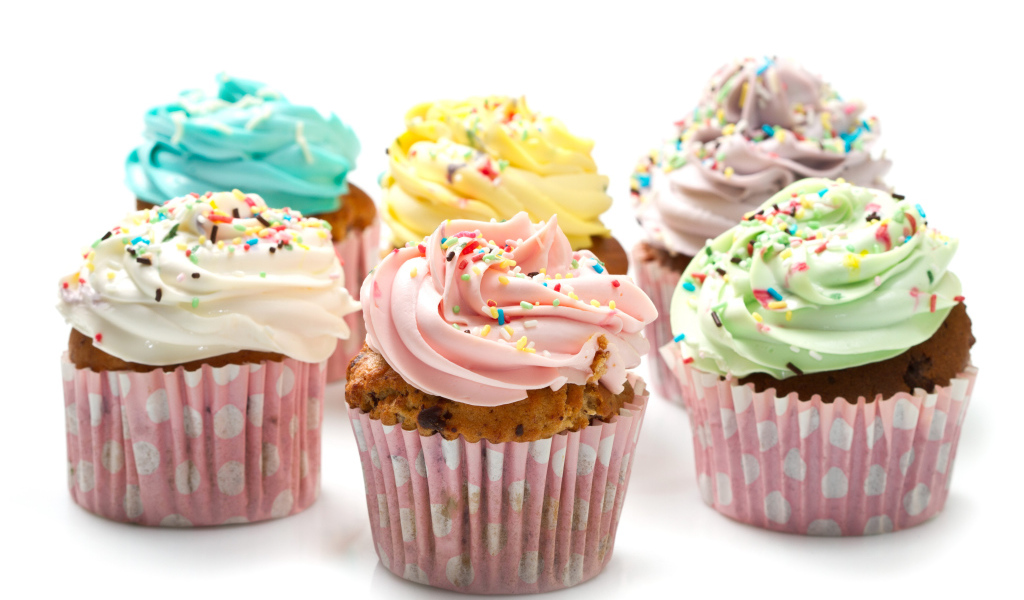 Сладкие кексы с кремом и посыпкой на белом фоне