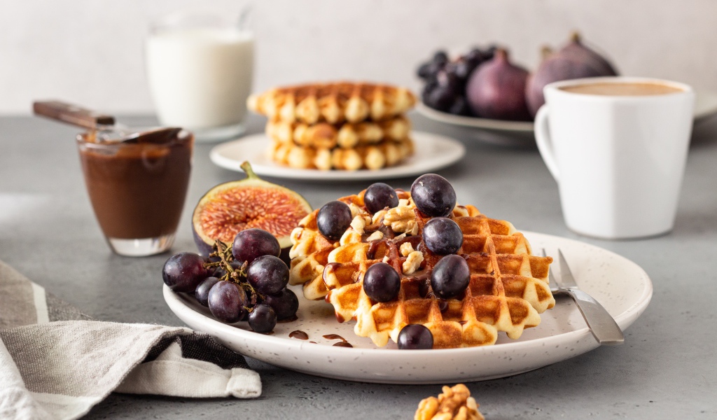 Сладкие вафли на тарелке с инжиром и виноградом
